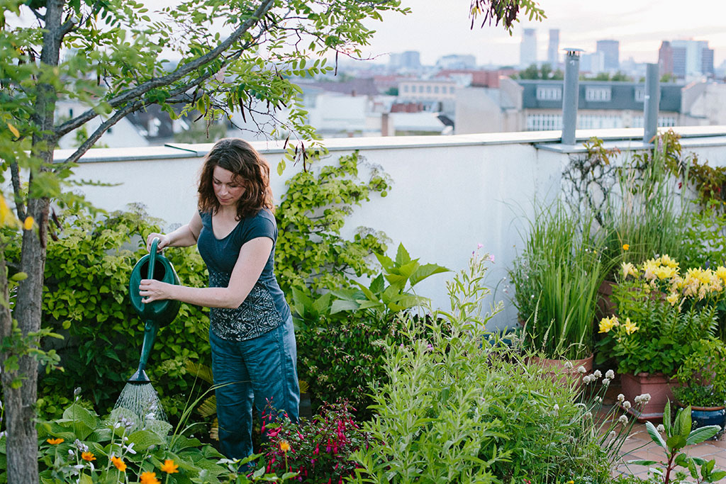 woman waters plants on roof garden