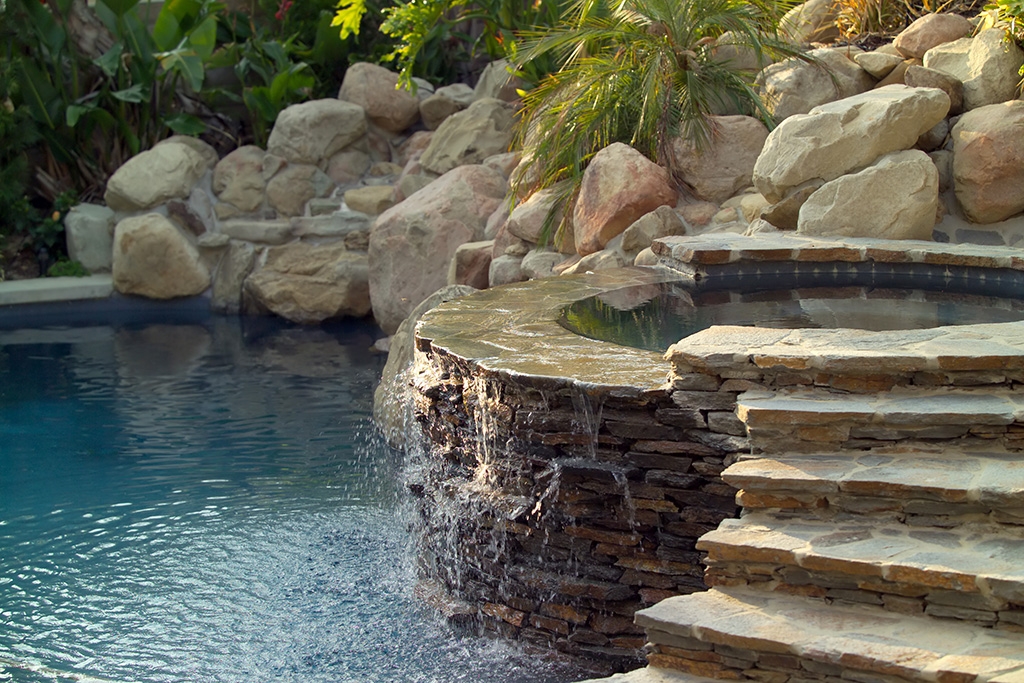 Outdoor pool with built in stone hot tub waterfall and stairs