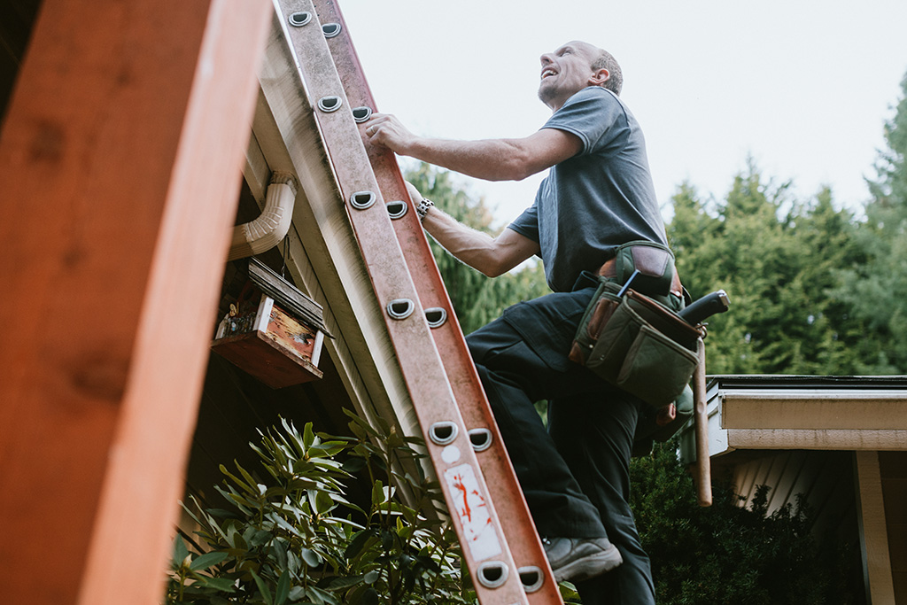 Man climbing ladder outside home
