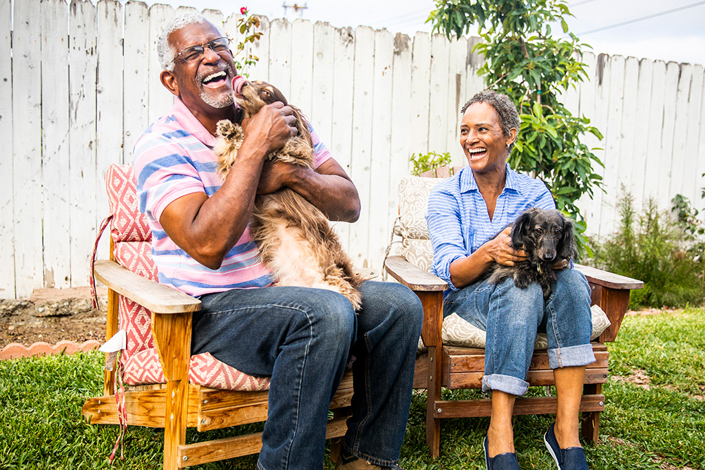 Older man and woman outside laughing with dogs