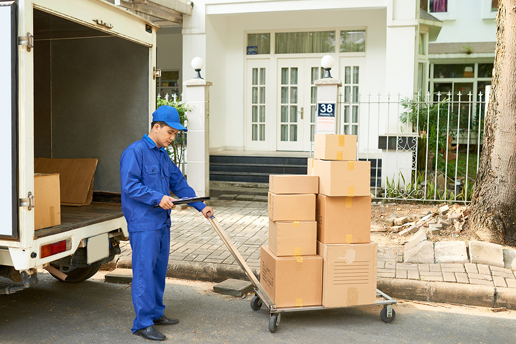 Man next to moving truck with boxes on a handcart