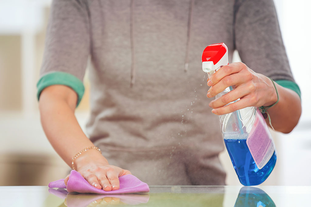 Woman cleaning counter with cleaning products