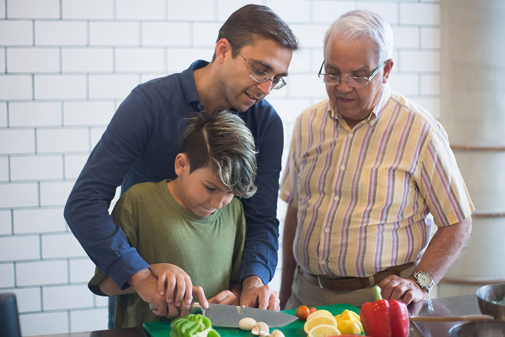 Two older men and one child cutting vegetables