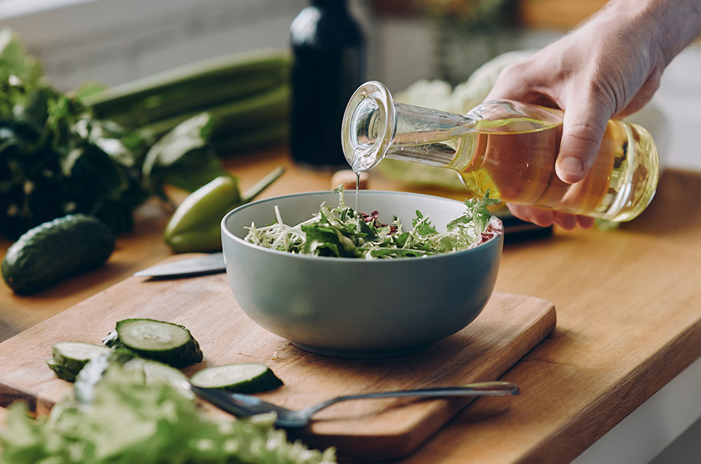 Person pouring dressing over salad