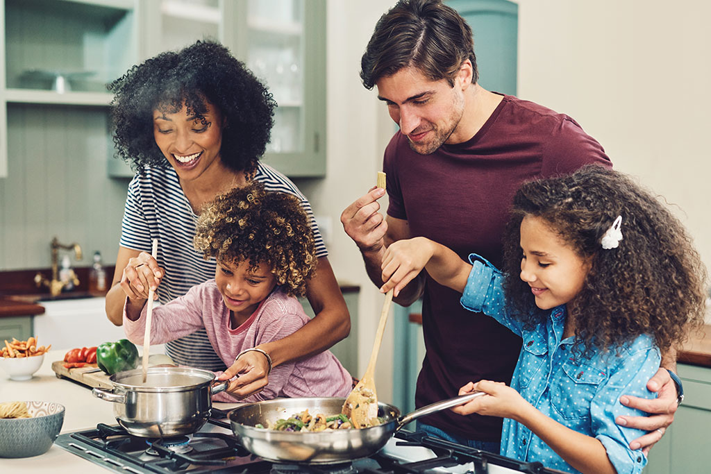 Family in kitchen making food