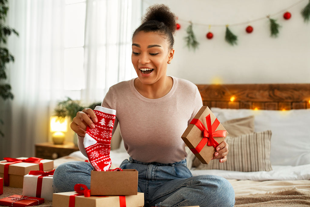 Young woman opening Christmas present that is socks