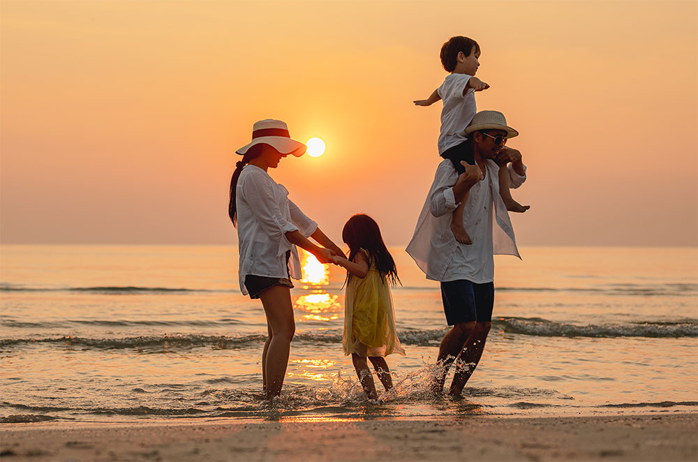 Family playing on beach at sunset