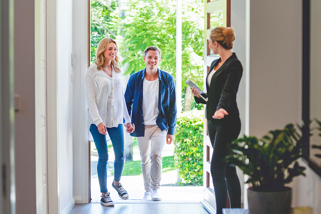 Couple walking into house with real estate agent