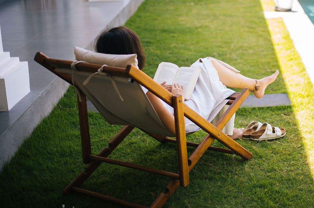 Woman sitting in lounge chair reading book