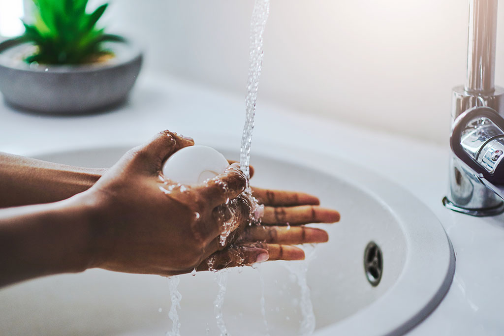 Woman washing hands under sink