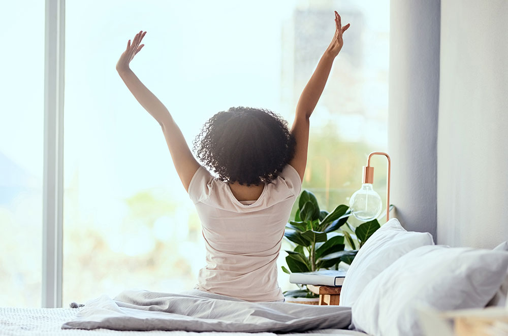 Woman waking up stretching in bed