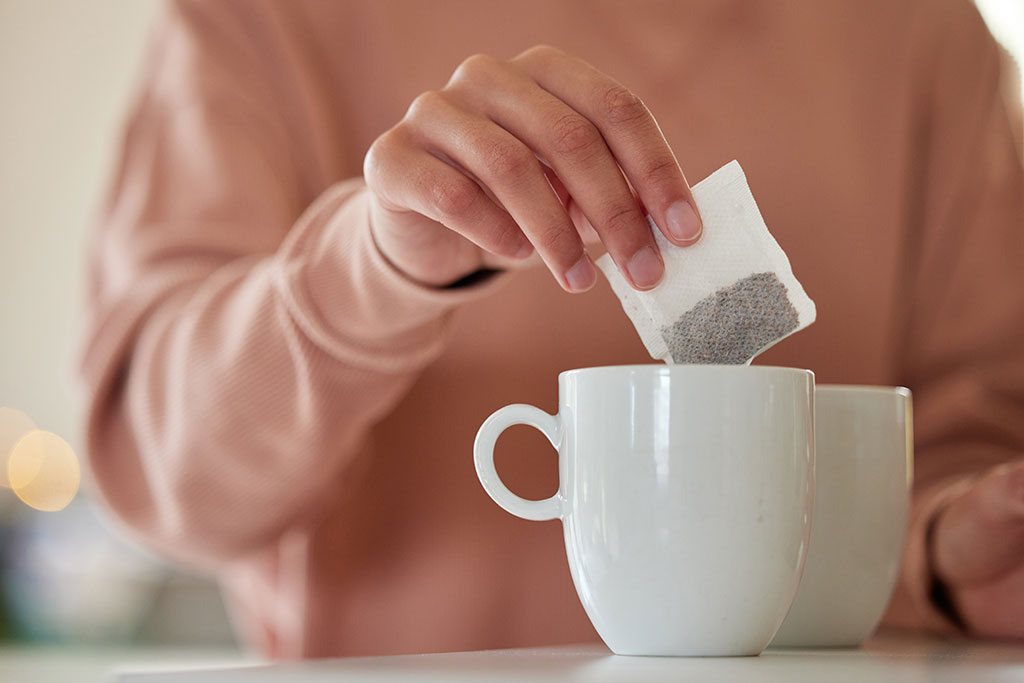 Person putting tea bag into mug