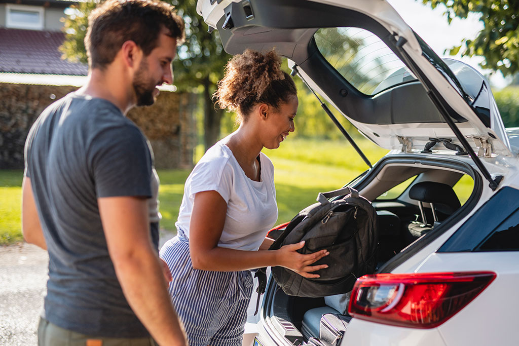 Younger couple packing car for trip