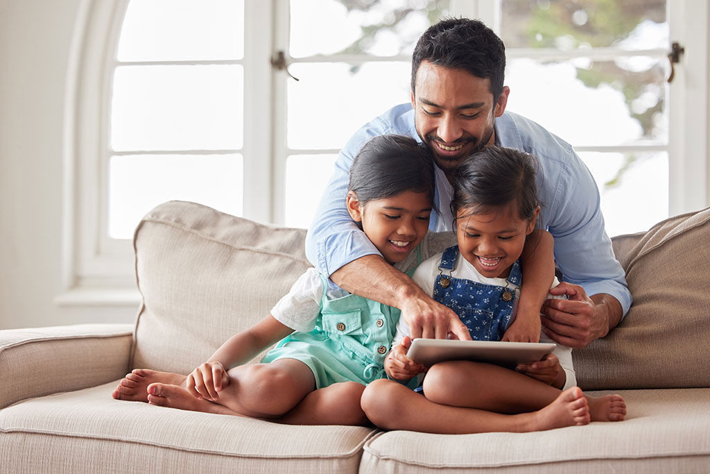 Dad reading to daughters on couch at home