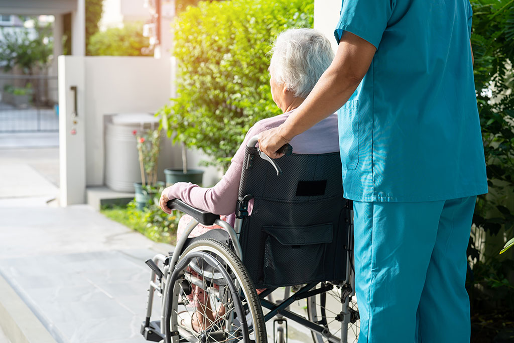 Nurse pushing older woman in wheel chair