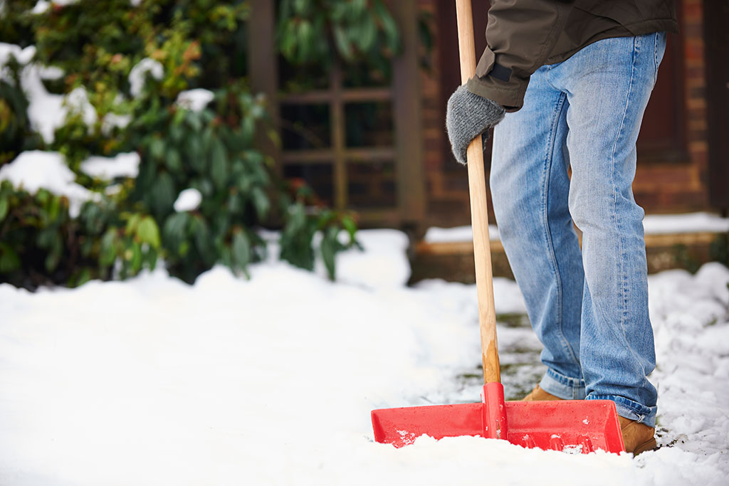 Man shoveling snow in front of house