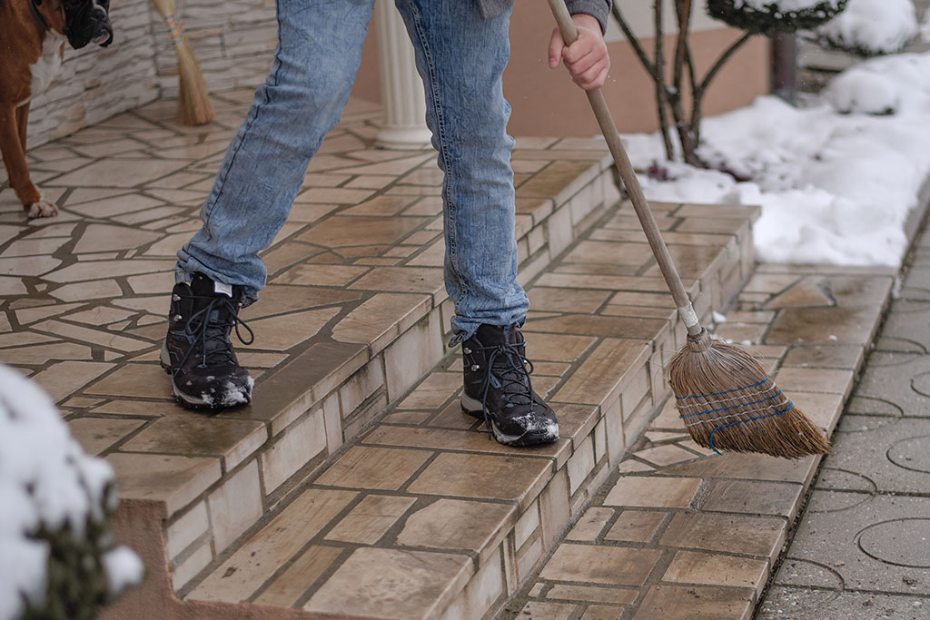 Person sweeping snow off patio