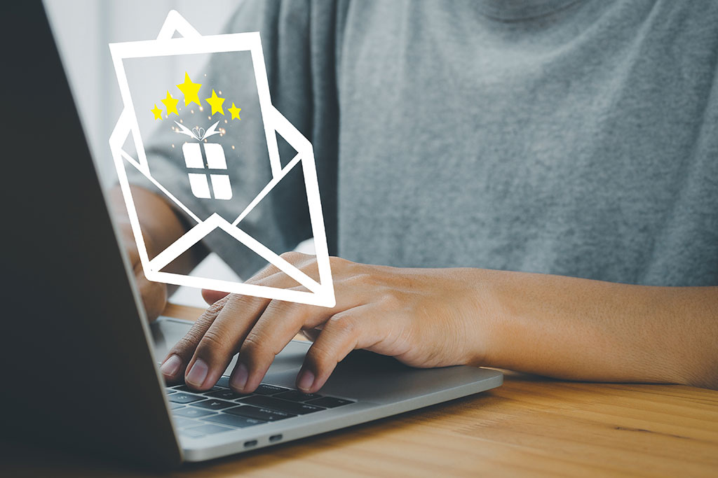 Opening email gift icon graphic above laptop