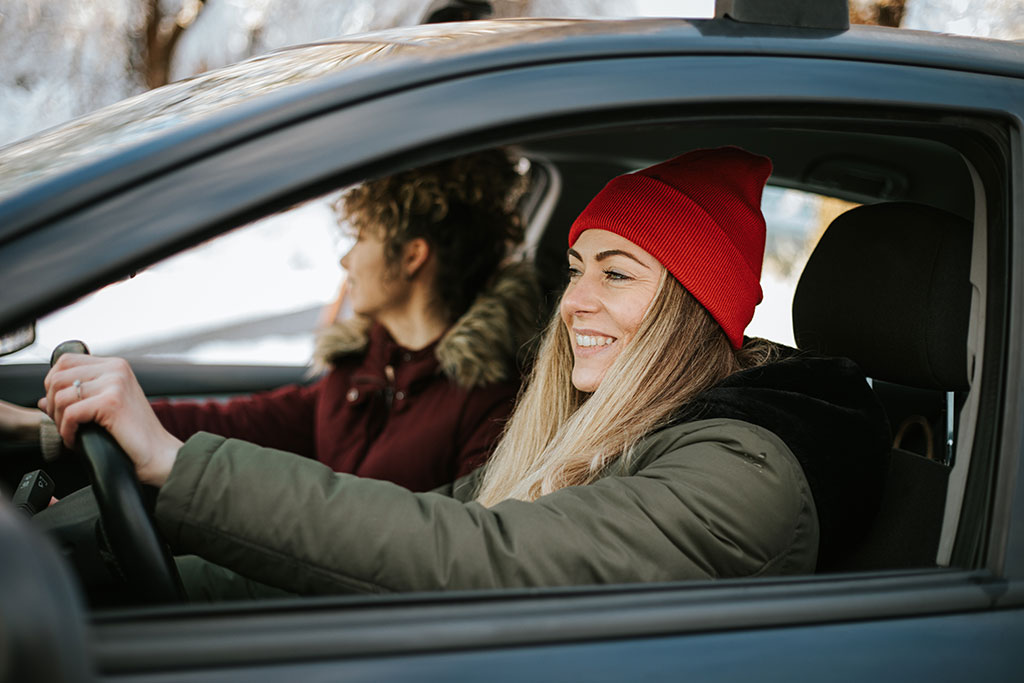 Friends driving in car with windows down in winter