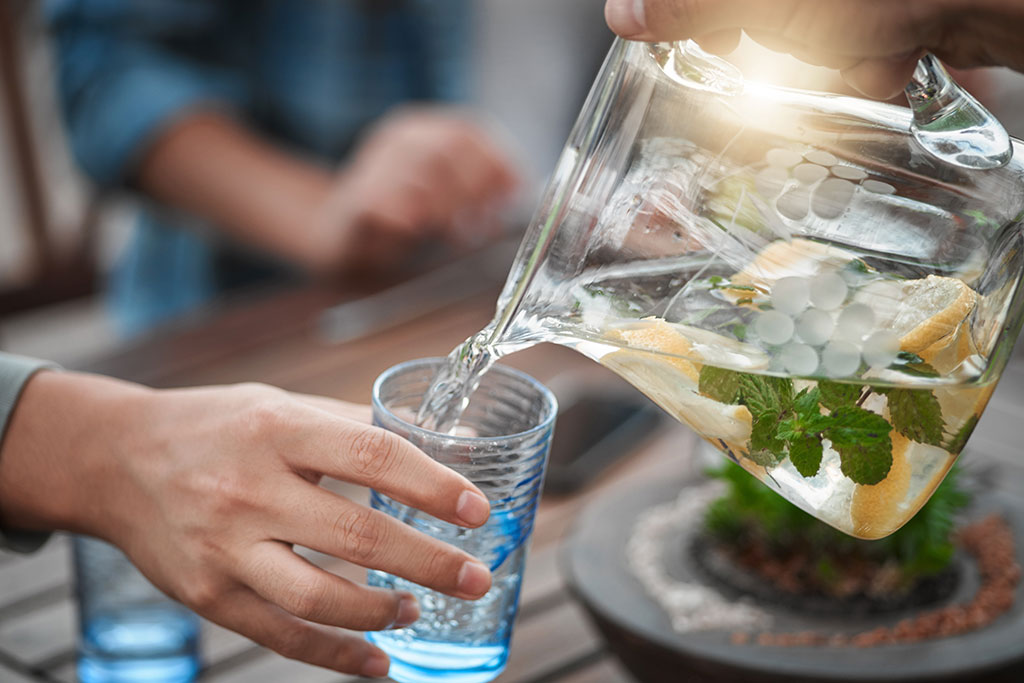 Pouring water into cup with pitcher