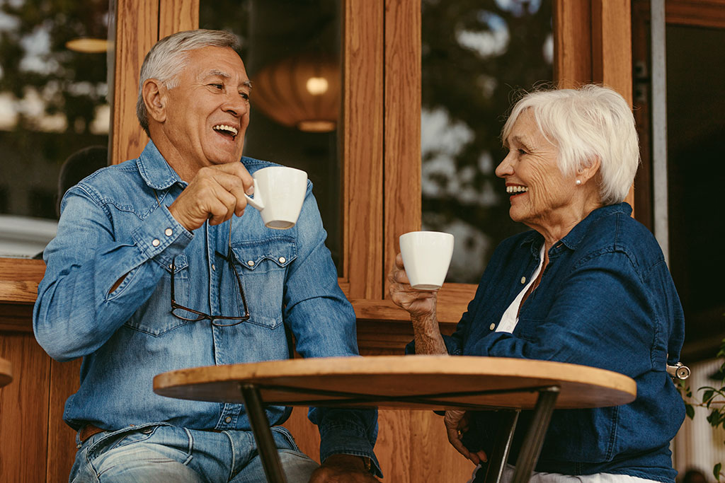 Older couple drinking coffee outside coffee shop