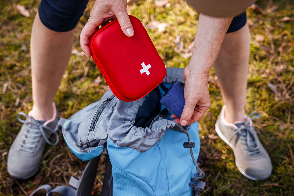 Person putting first aid kit in bag