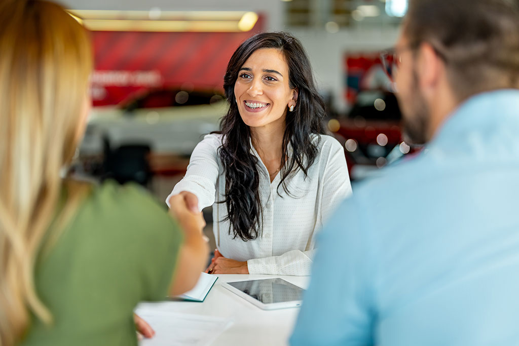 Car sales woman shaking hands with clients