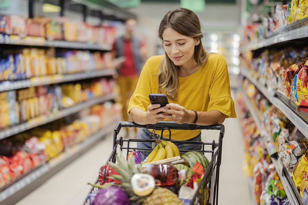 Woman grocery shopping looking at phone