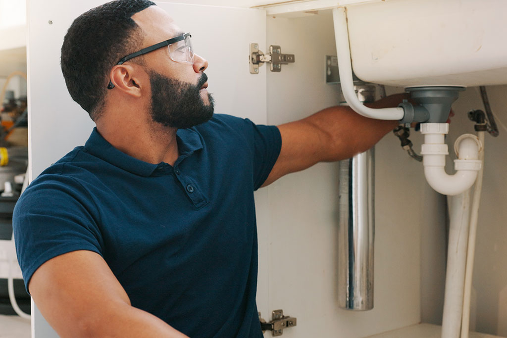 Man looking under sink for leak