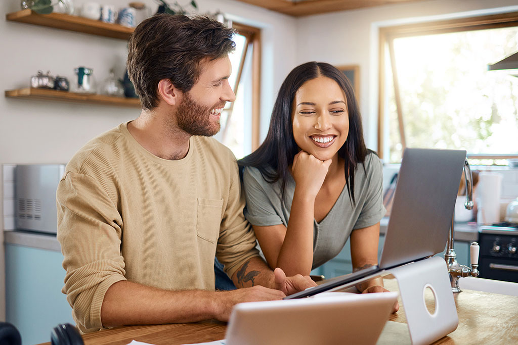 Happy couple looking at laptop
