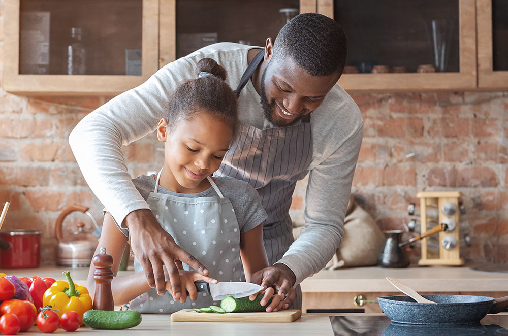 Dad and daughter cutting cucumber for dinner